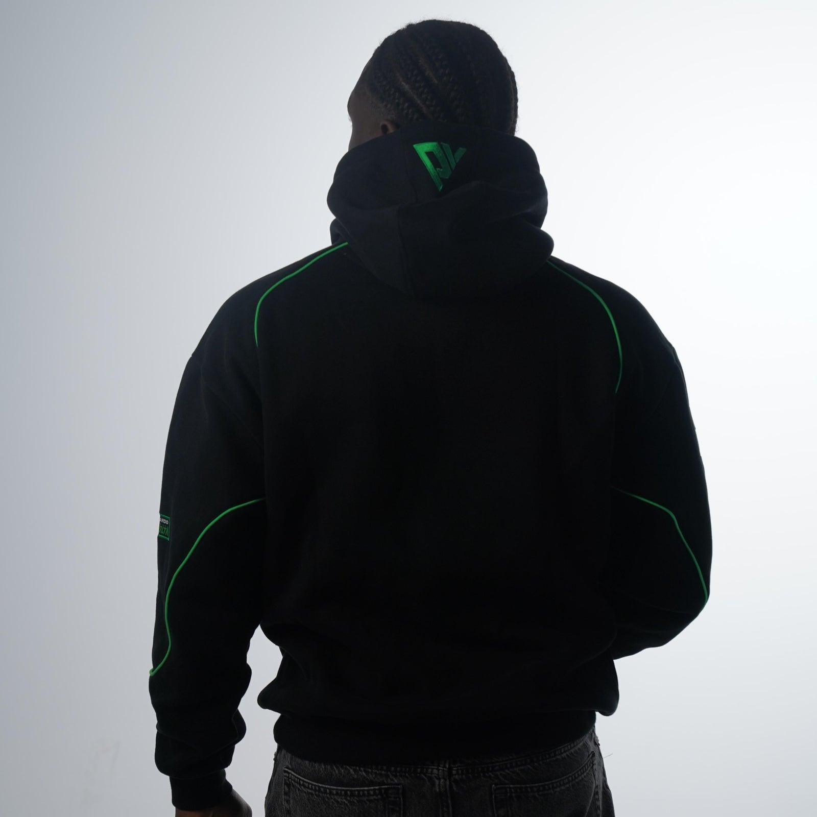 Person wearing a black hoodie with green accents on a white background