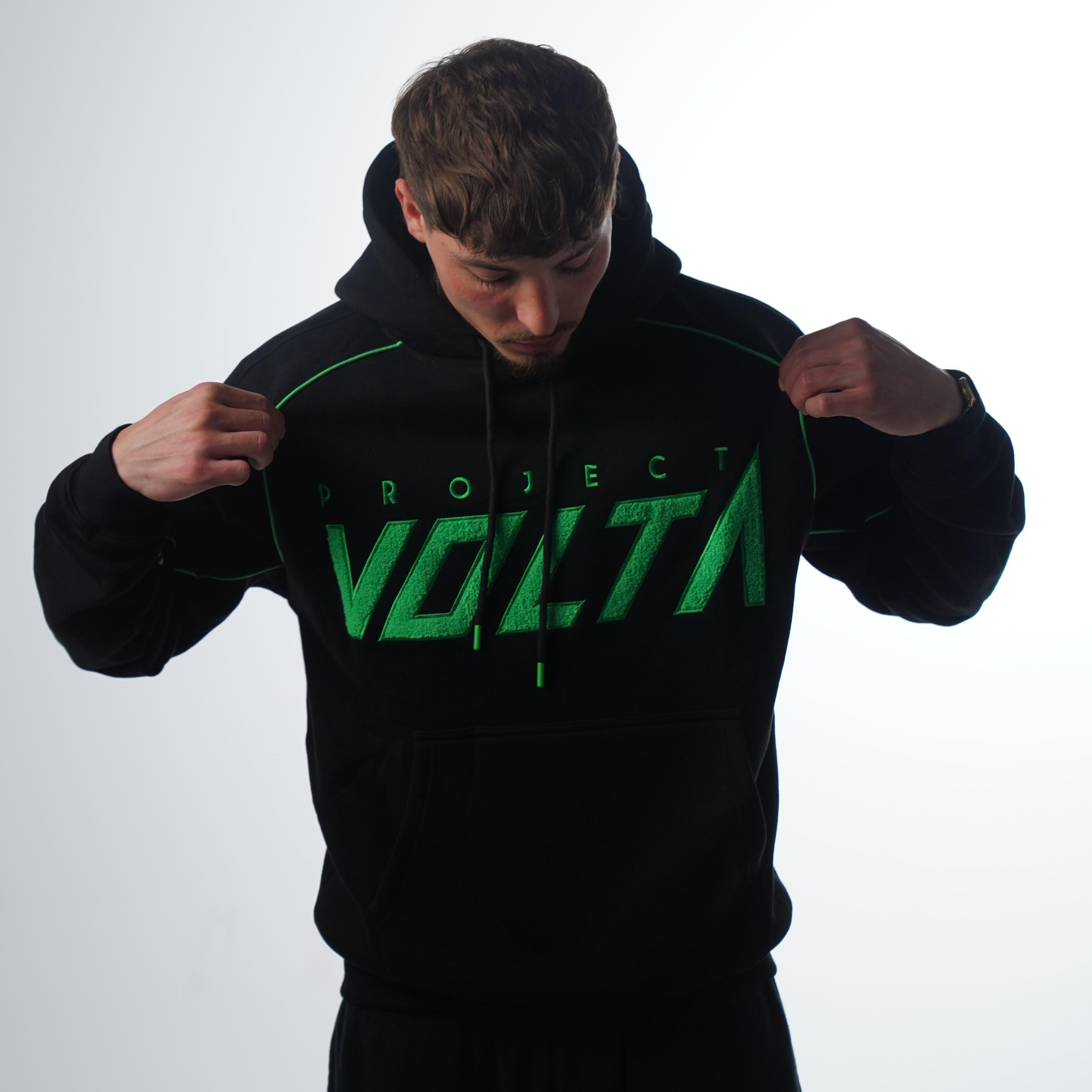 Person pointing a black hoodie with green text on a white background