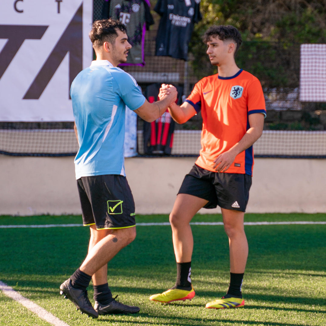 Two soccer players shaking hands on a soccer field with a blurred background