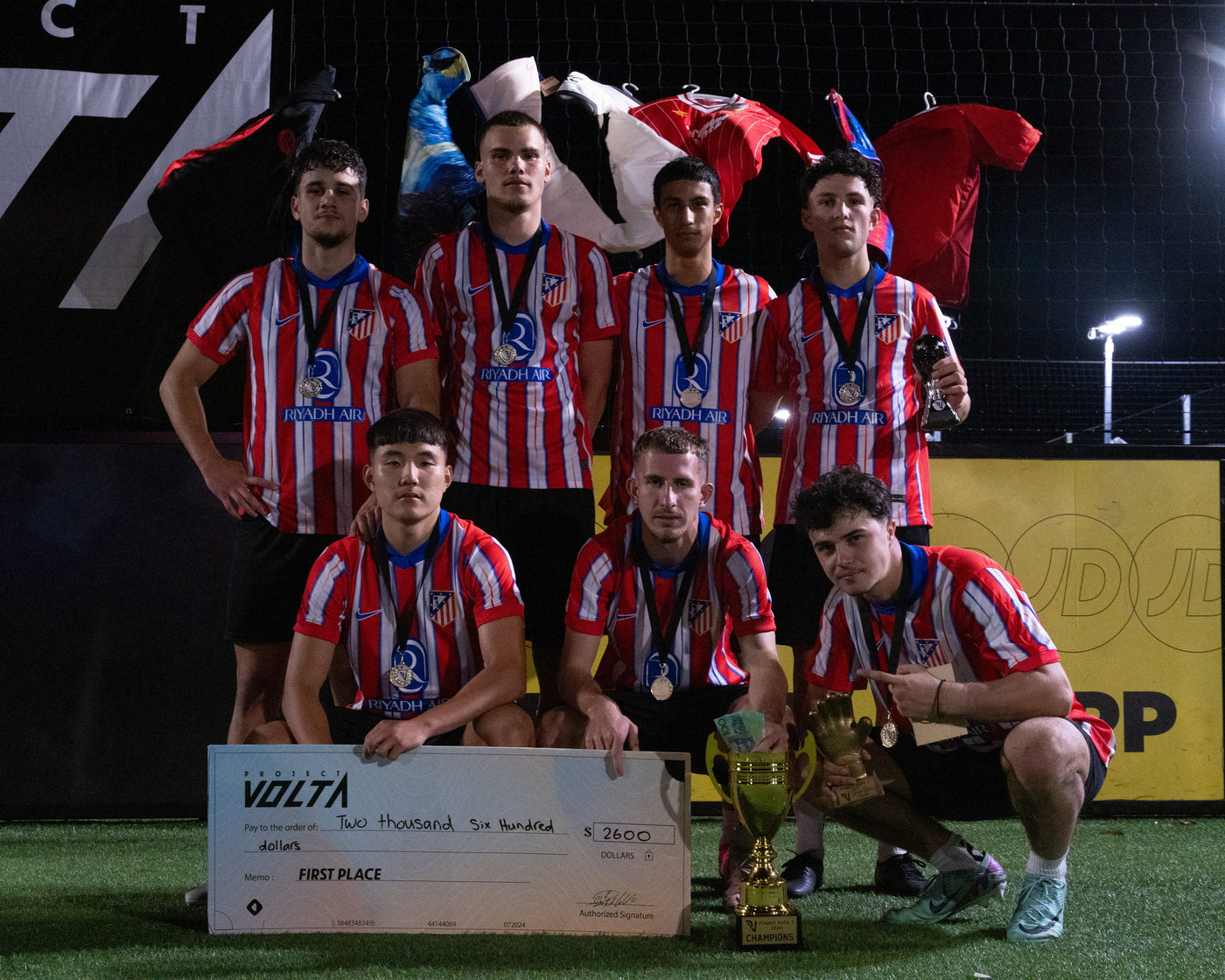 PV2 winning team lifting the trophy under the lights